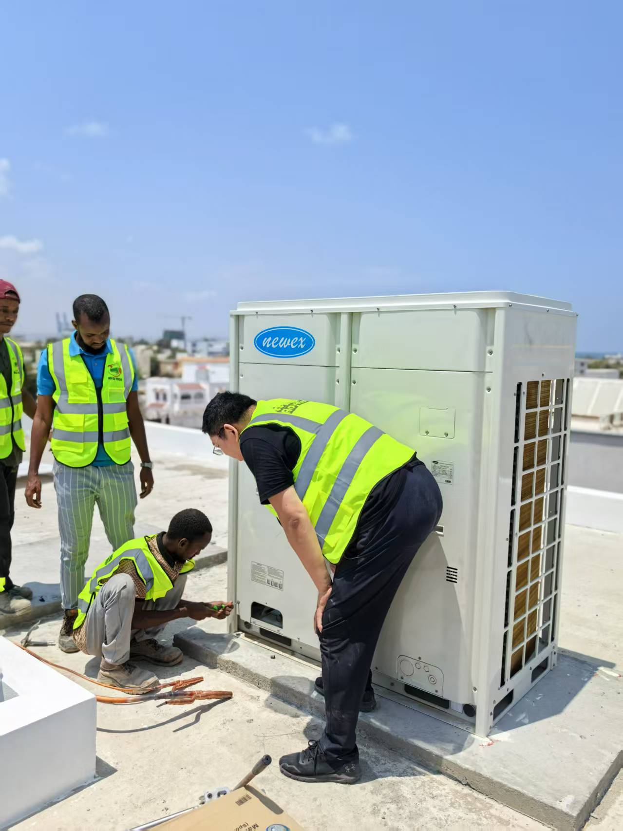 Displays the setup of rooftop air conditioning units in the Djibouti commercial building, highlighting the engineering efforts and equipment used by NEWEX.
